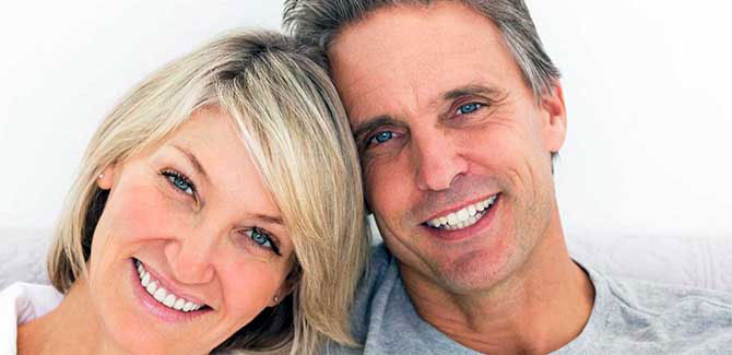 A man and woman are smiling together in a close embrace, both appearing happy and content.