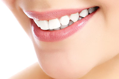 The image shows a close-up of a person s face with a focus on their teeth and lips, highlighting a smile with white teeth.