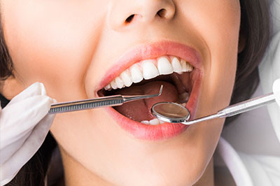 A woman s mouth being worked on by dental professionals with specialized equipment.
