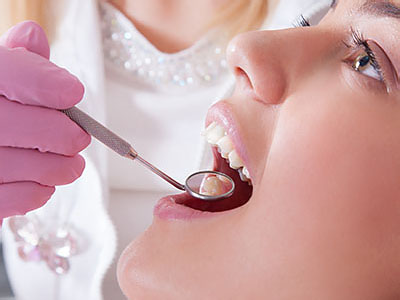 A dental professional using a dental drill on a patient s teeth.