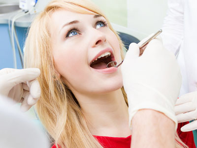 A woman receiving dental care with a smile on her face while seated in a dental chair.